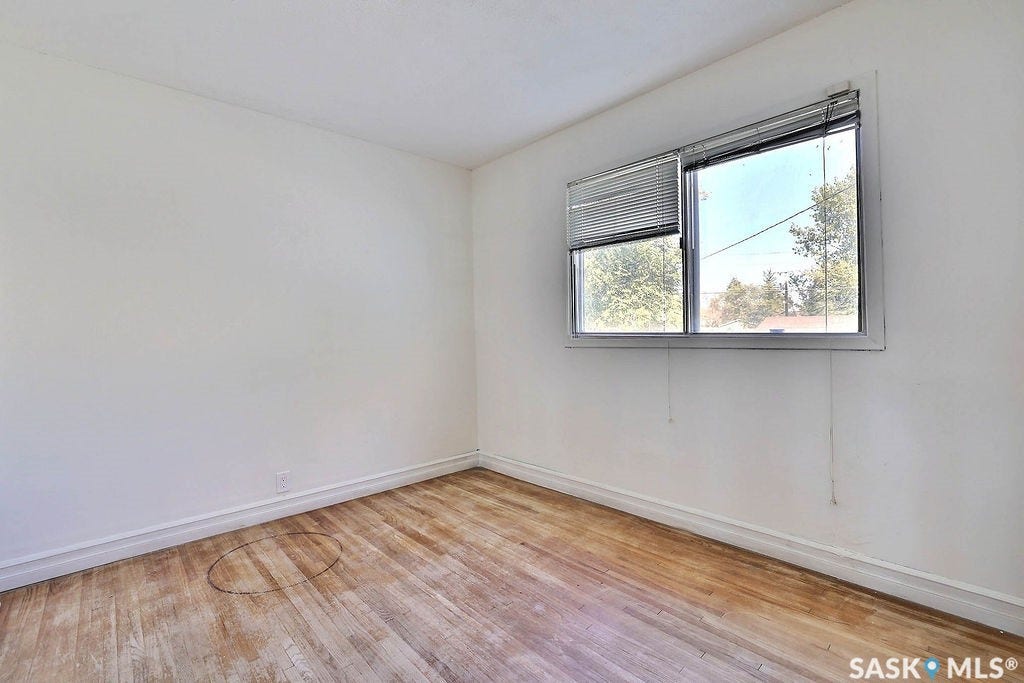 Wood-finish flooring with white baseboards and neutral wall paint