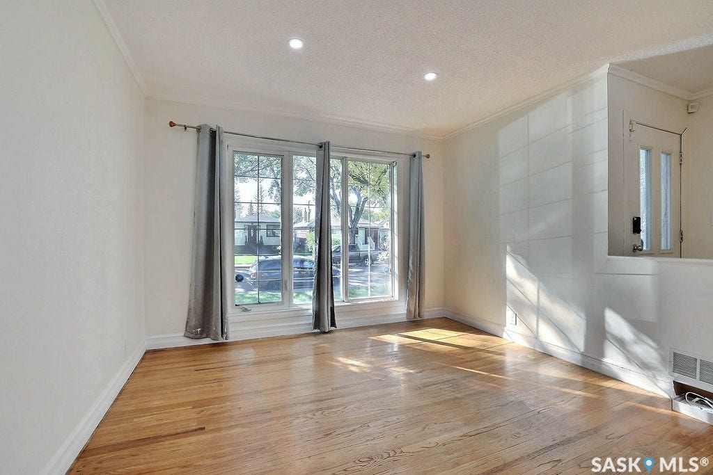 Hardwood flooring, recessed lighting, white trim, multiple windows with grid detailing, and a partially paneled wall