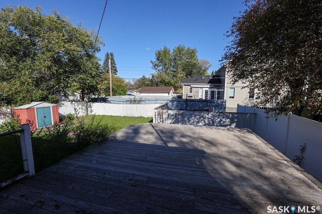 Expansive outdoor deck with a lower lawn area and a storage shed