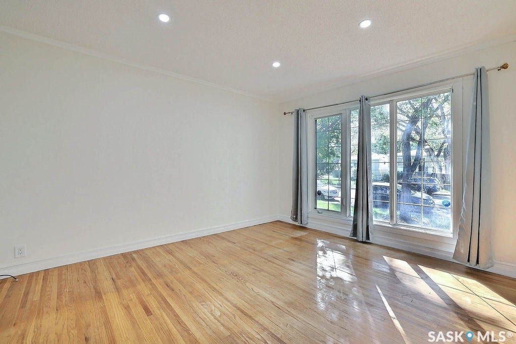 Hardwood flooring, recessed lighting, white crown molding, and large windows with exterior foliage