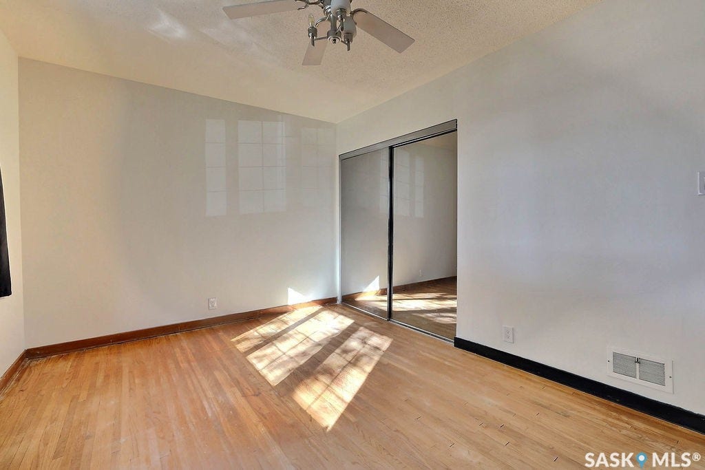 Wood-finish flooring with a ceiling fan and mirrored closet doors
