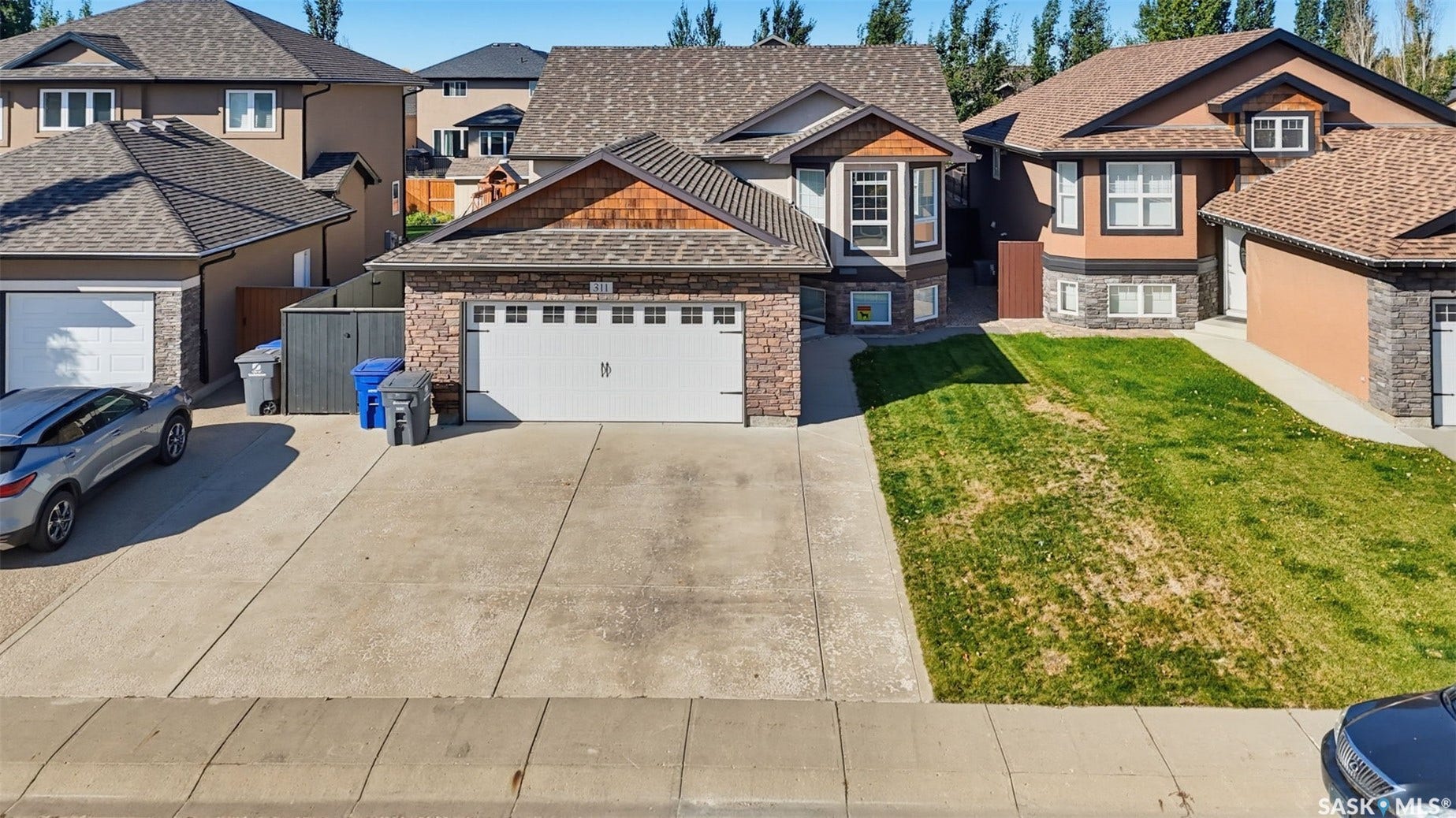 Front exterior featuring a multi-tone roof, stone and siding facade, an attached double garage, and a concrete driveway