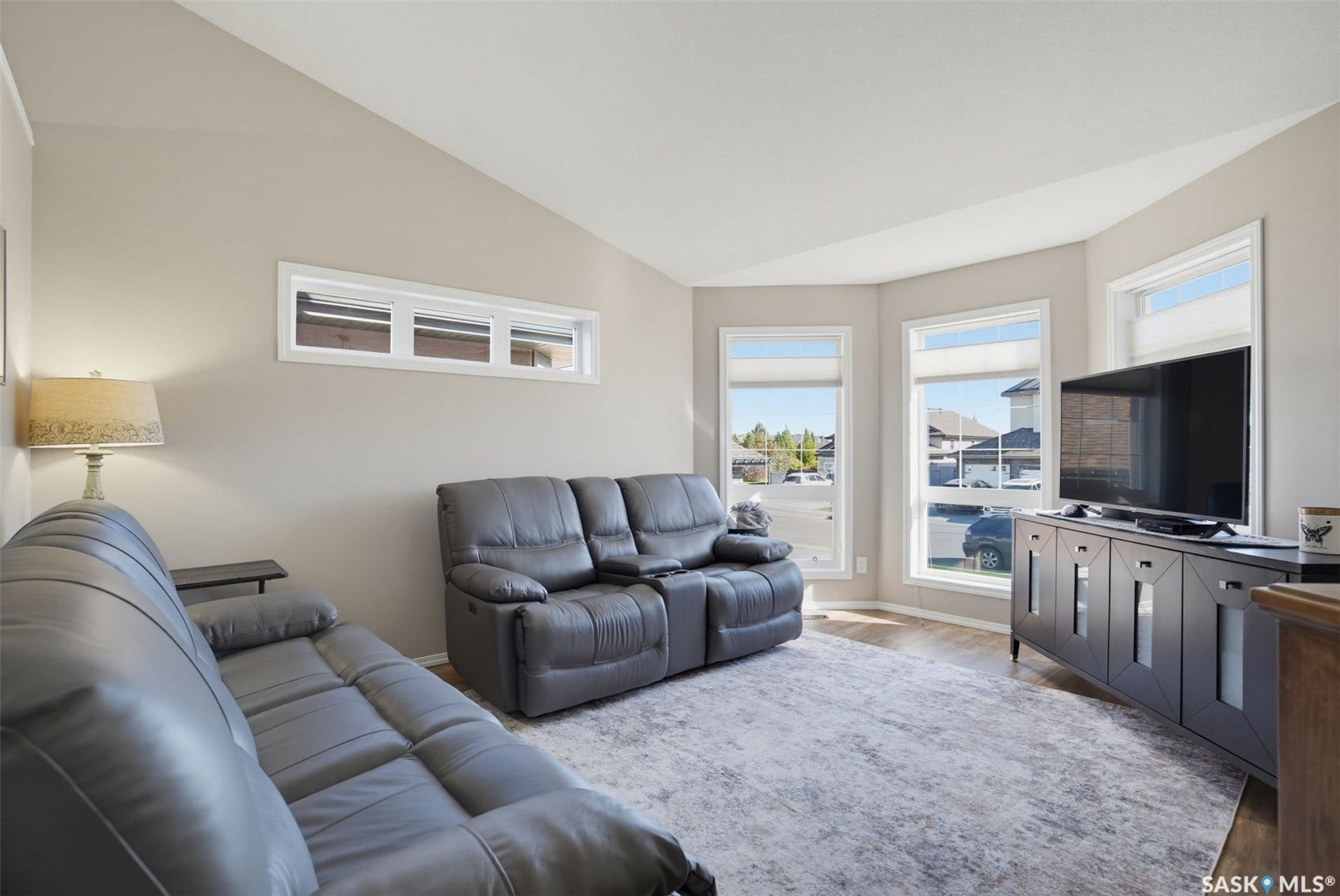Vaulted ceiling, wood-finish flooring, bay window configuration, transom window, and neutral wall tones