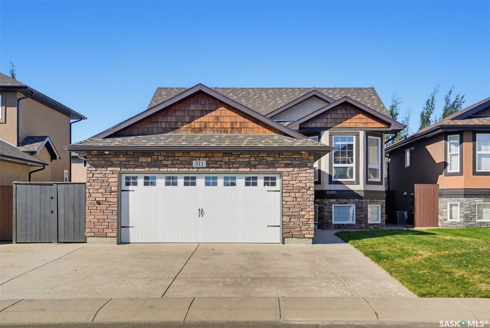 Stone veneer exterior with cedar shake accents, a two-car garage, and a concrete driveway