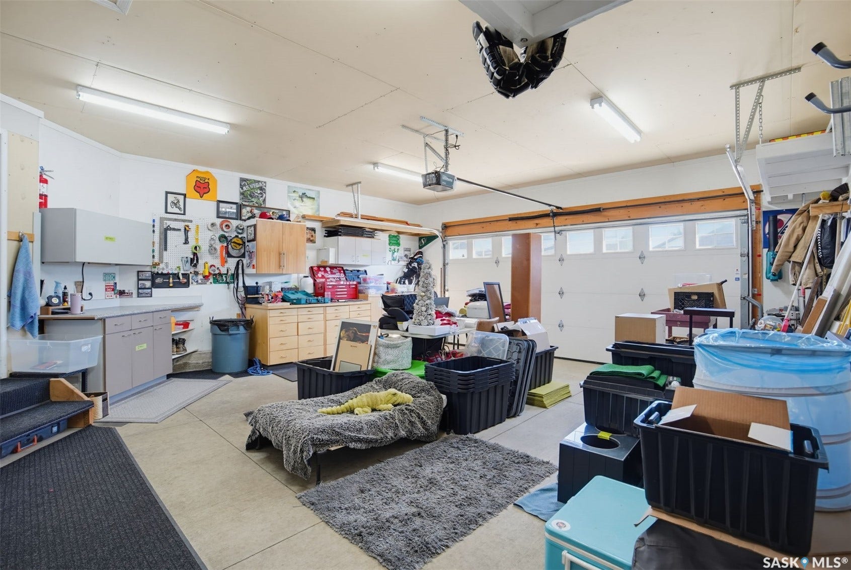 Attached garage with overhead lighting, built-in cabinetry, and a utility sink