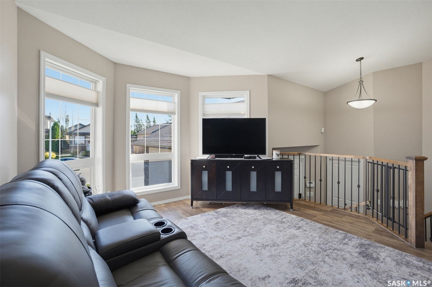 Recessed lighting, vaulted ceiling, bay window, wood-finish flooring, and wrought iron railing