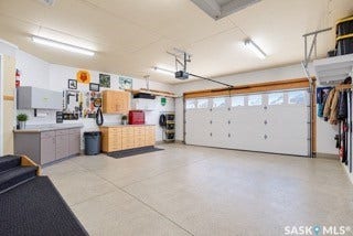 Spacious garage featuring a sectional overhead door with windows, built-in cabinetry, and wall-mounted storage racks-- AI generated