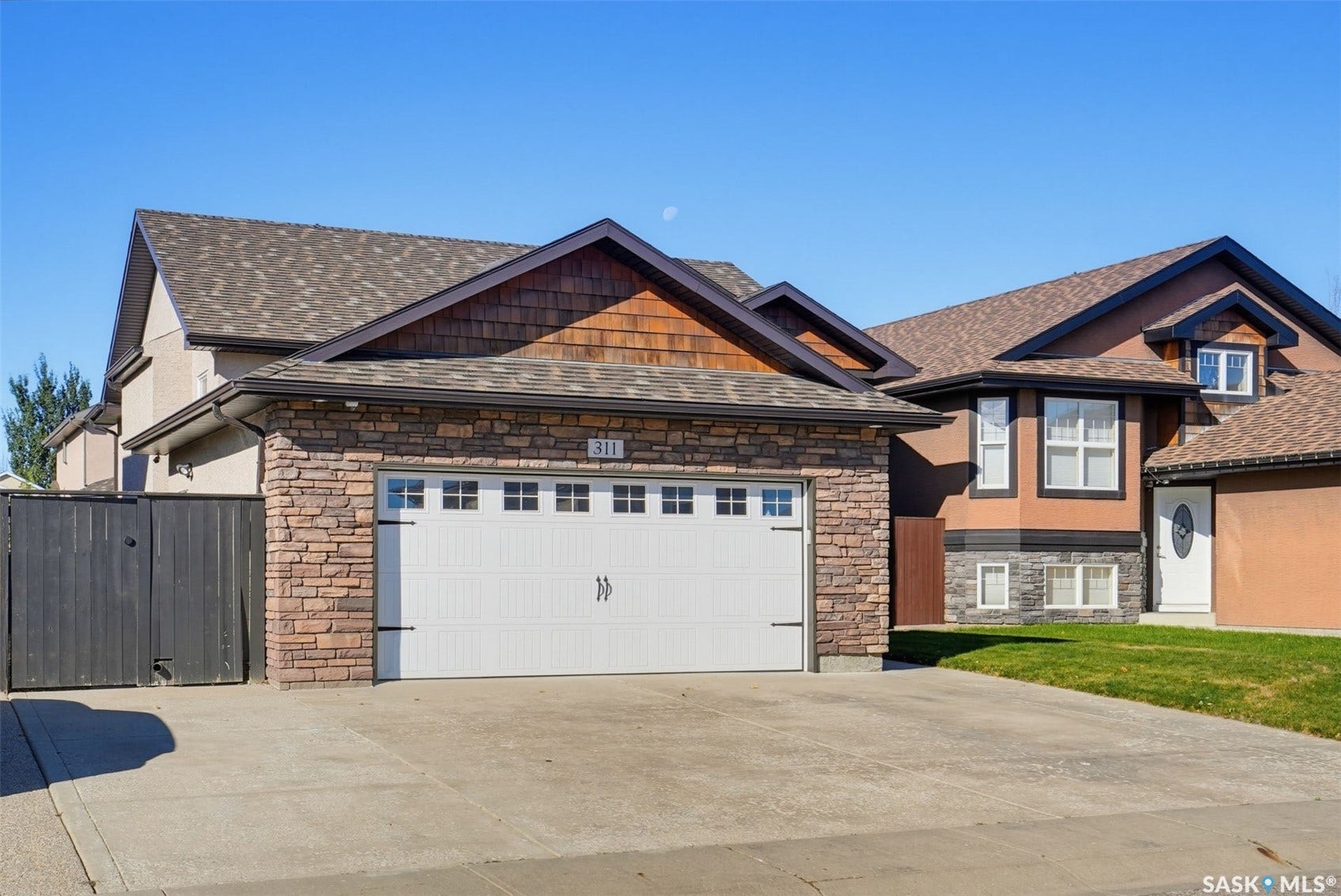 Attached two-car garage with stone veneer detailing and a white panel door