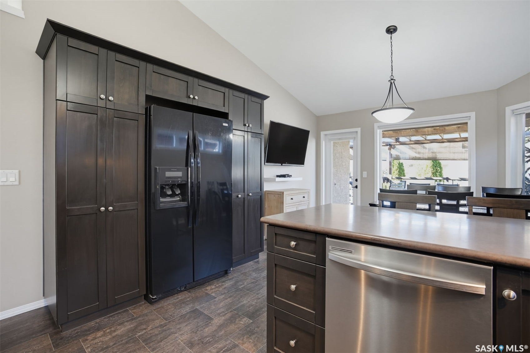 Dark wood-finish cabinetry providing ample storage, a stainless steel dishwasher, and a spacious kitchen island with a durable countertop