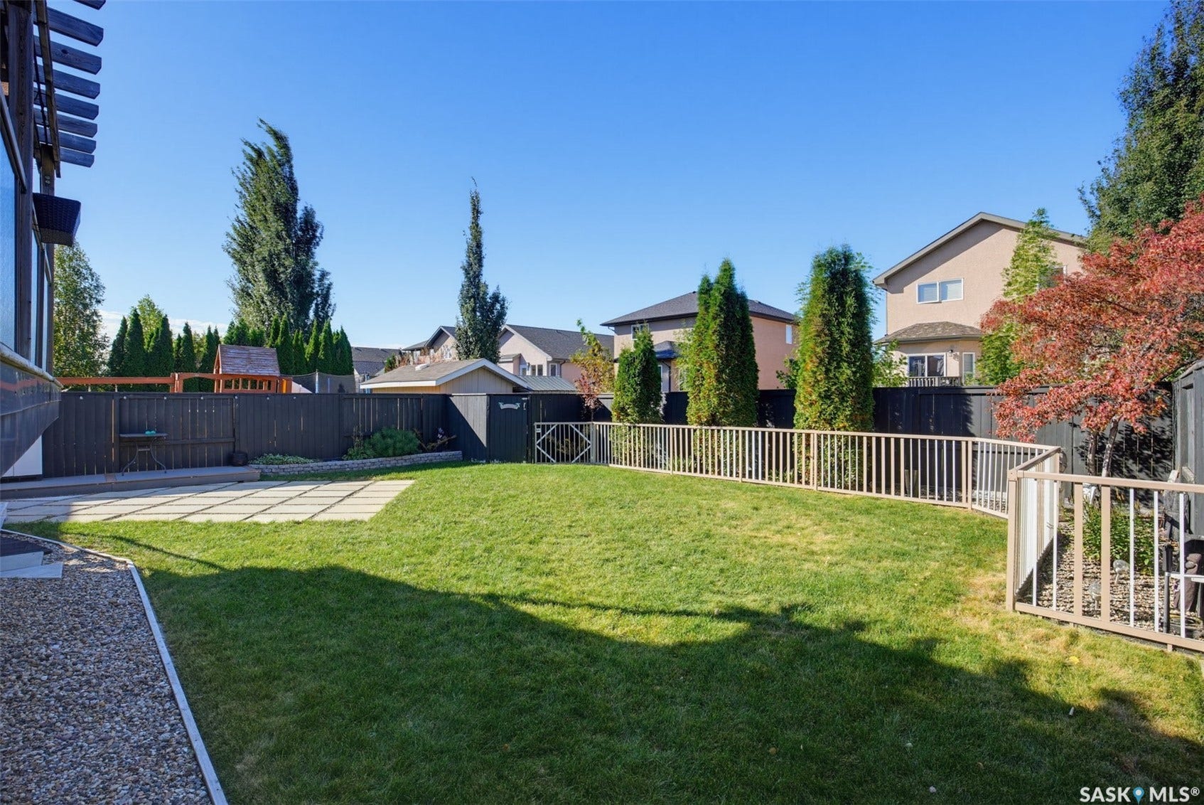 Expansive backyard featuring a manicured lawn, established privacy fencing, and a dedicated patio area