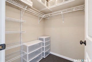 Walk-in closet featuring wire shelving, wire hanging rods, and dark wood-finish flooring-- AI Generated