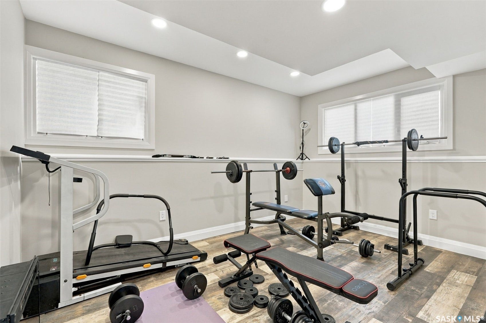 Recessed lighting, wood-finish flooring, accent wall trim, and multiple windows with privacy blinds