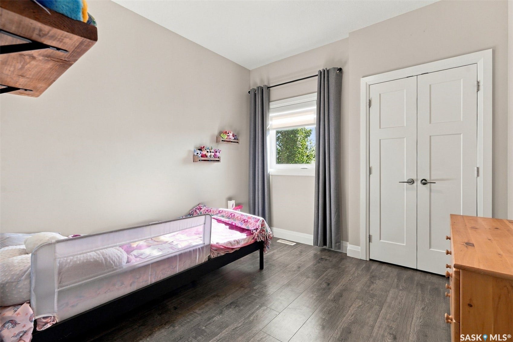 Wood-finish flooring, white window trim, and white paneled doors with contemporary hardware