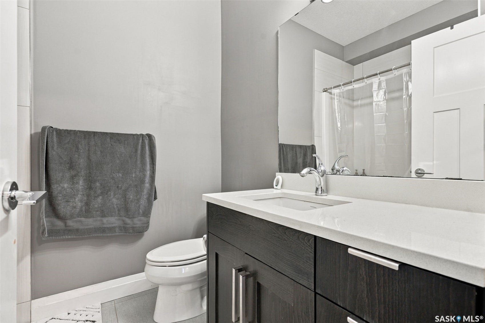 Dark wood-finish vanity with an integrated sink, white countertop, and polished chrome fixtures