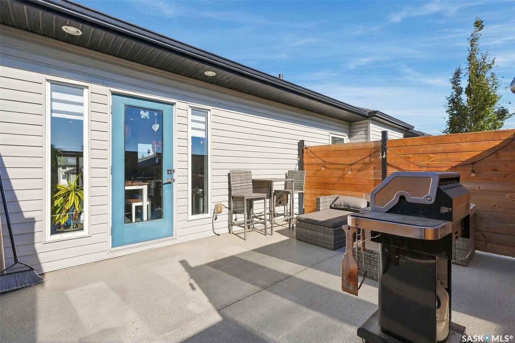 Spacious concrete patio featuring a privacy fence, exterior door with glass insert, and two vertical windows