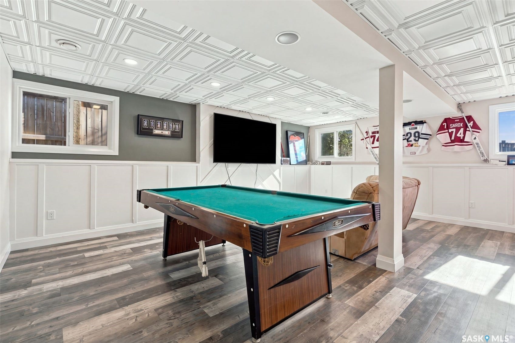 Wood-finish flooring, white wainscoting, recessed lighting, and multiple windows
