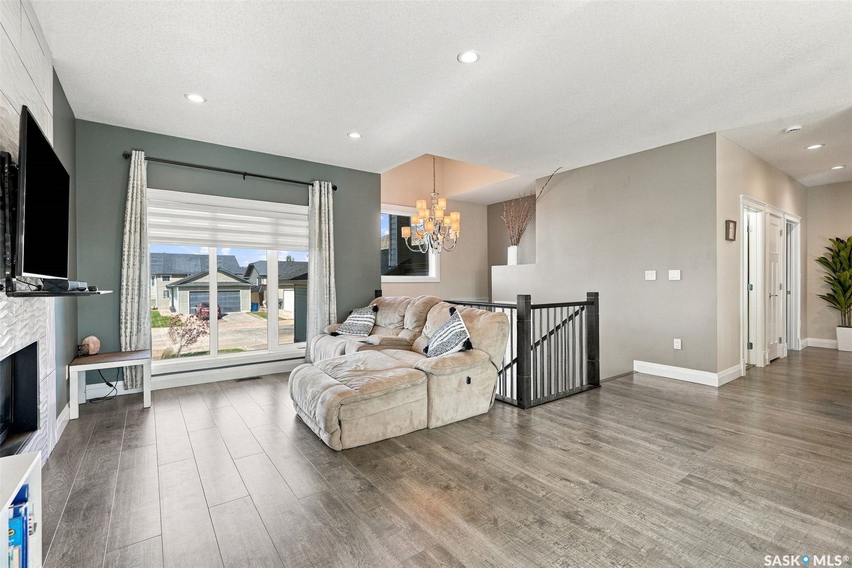 Spacious living area featuring wood-finish flooring, recessed lighting, and a large picture window with window treatments