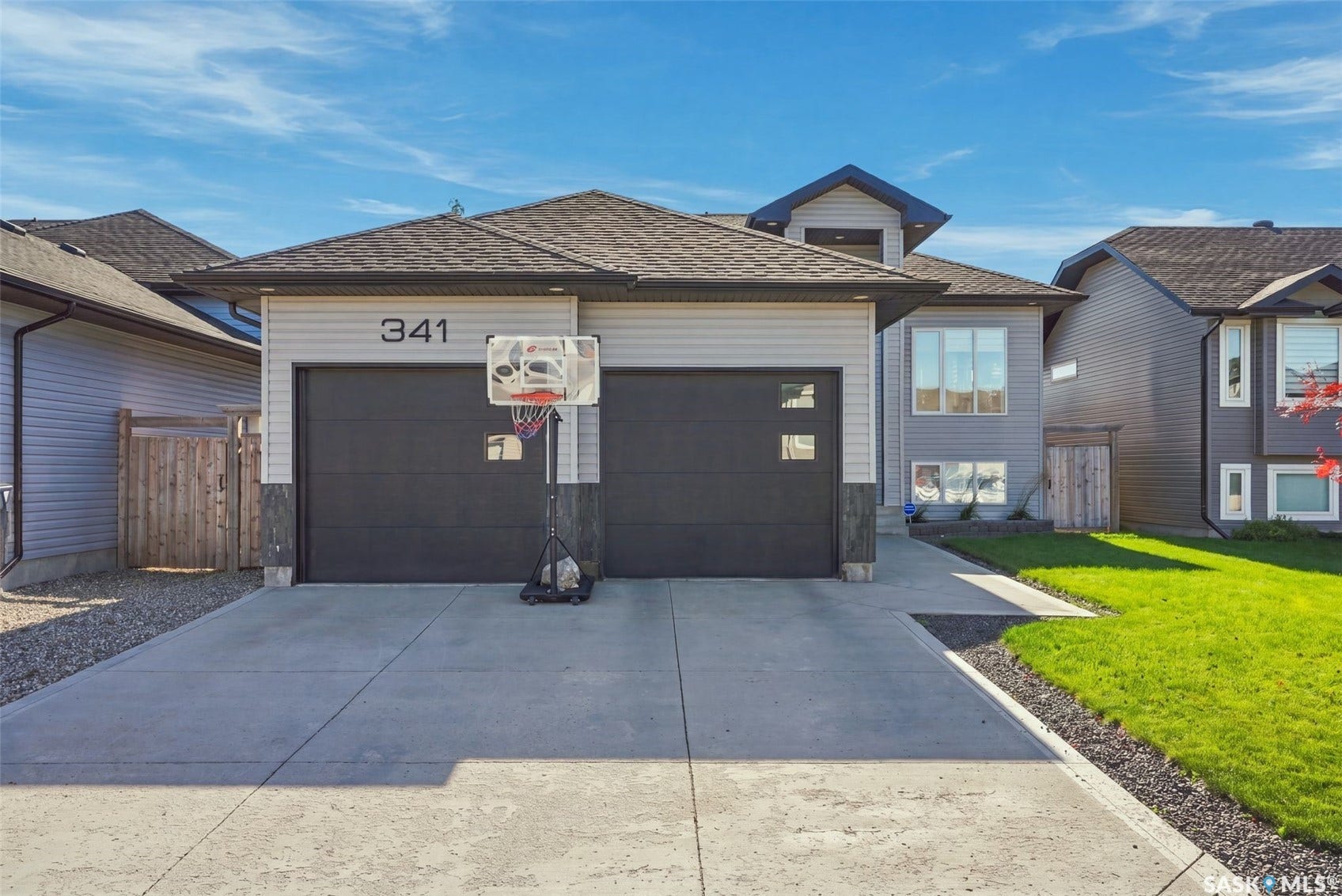 Light-toned siding exterior with dark-toned garage doors and a paved concrete driveway