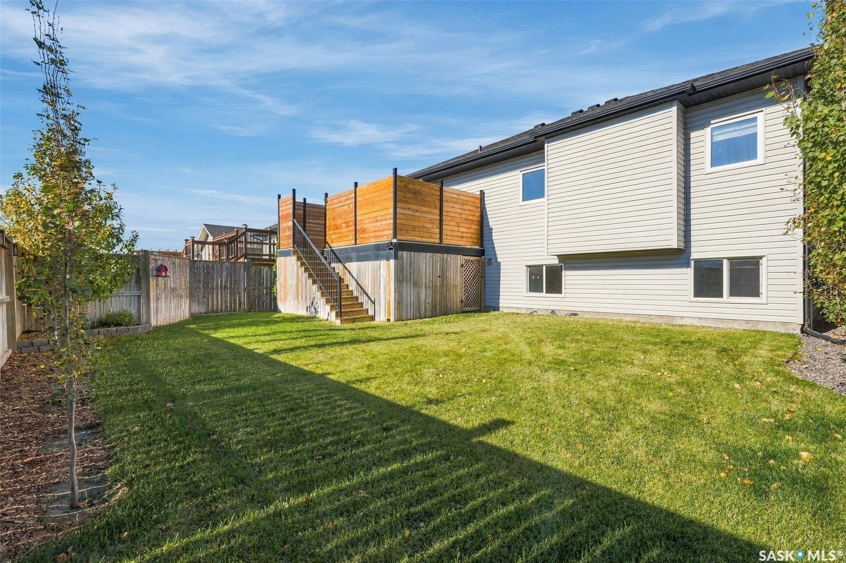 Spacious backyard with a raised wood deck, privacy fencing, and a manicured lawn