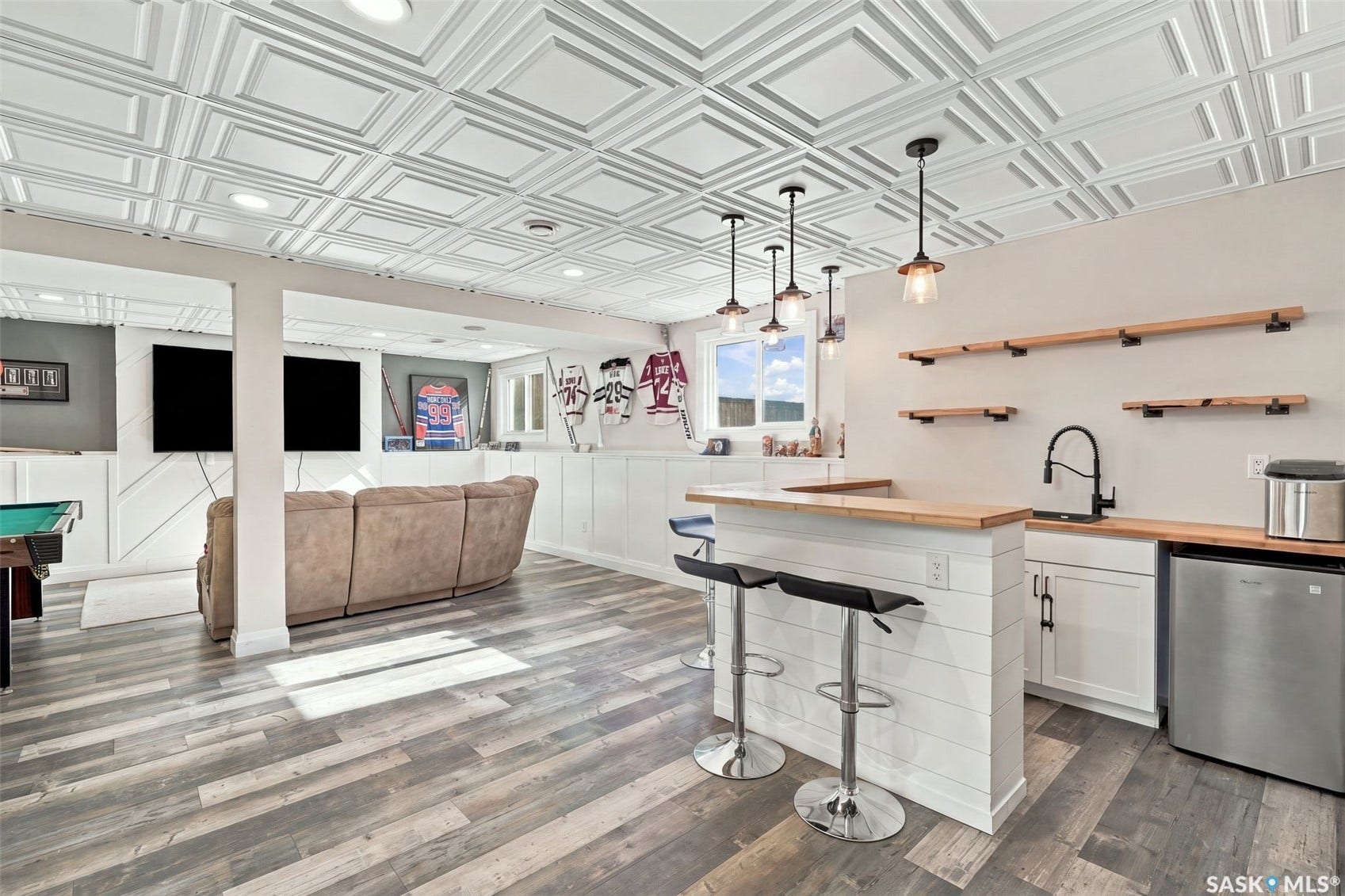 Wet bar with wood-finish countertop, crisp white cabinetry, and pendant lighting