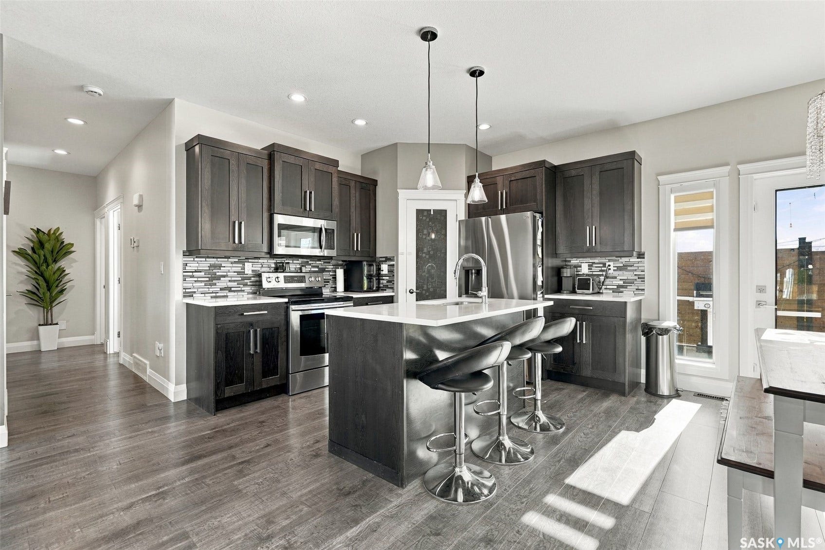 Gourmet kitchen with dark wood-finish cabinetry, stainless steel appliances, a center island with pendant lighting, and wood-finish flooring
