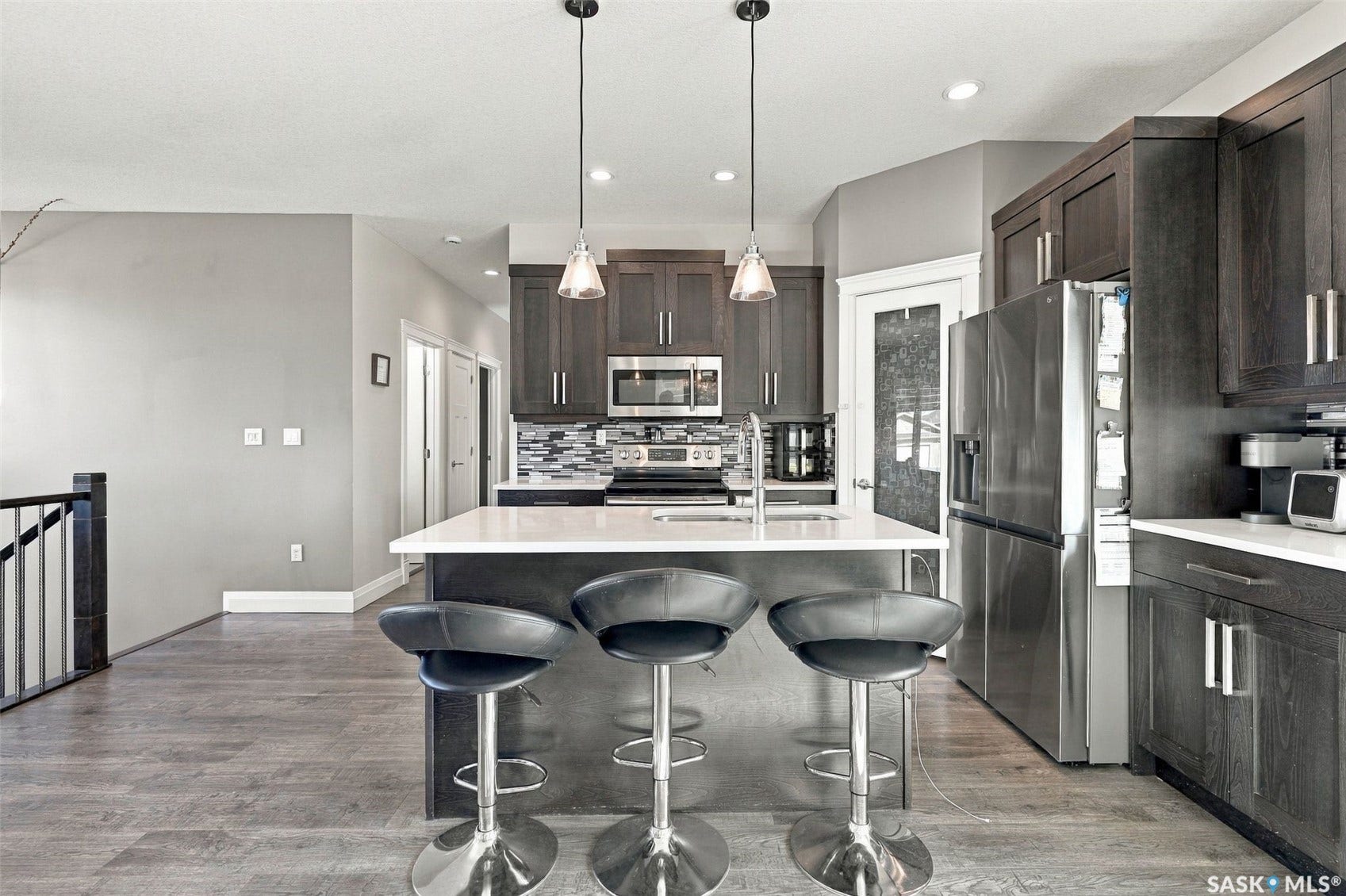 Kitchen featuring dark wood-finish cabinetry, stainless steel appliances, a center island with a white countertop, and wood-finish flooring