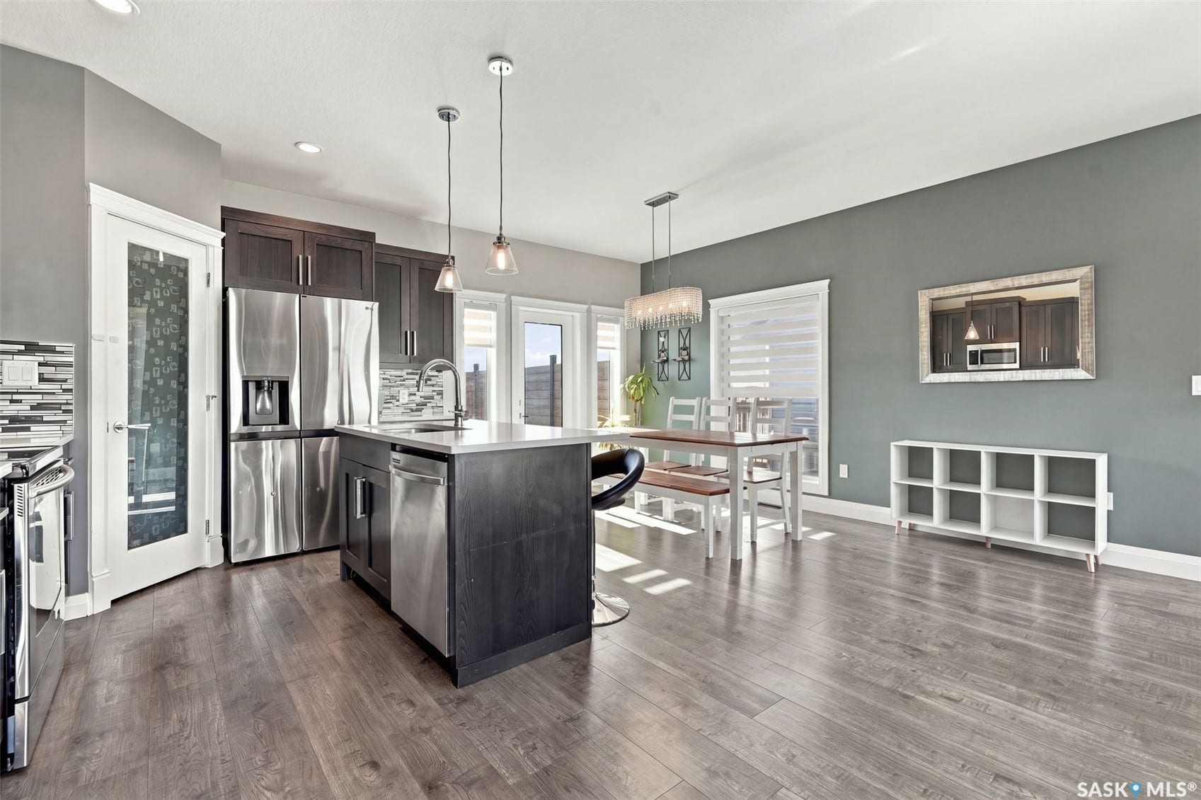 Open-concept kitchen and dining area featuring wood-finish flooring, dark wood cabinetry, a center island with a light-toned countertop, and stainless steel appliances
