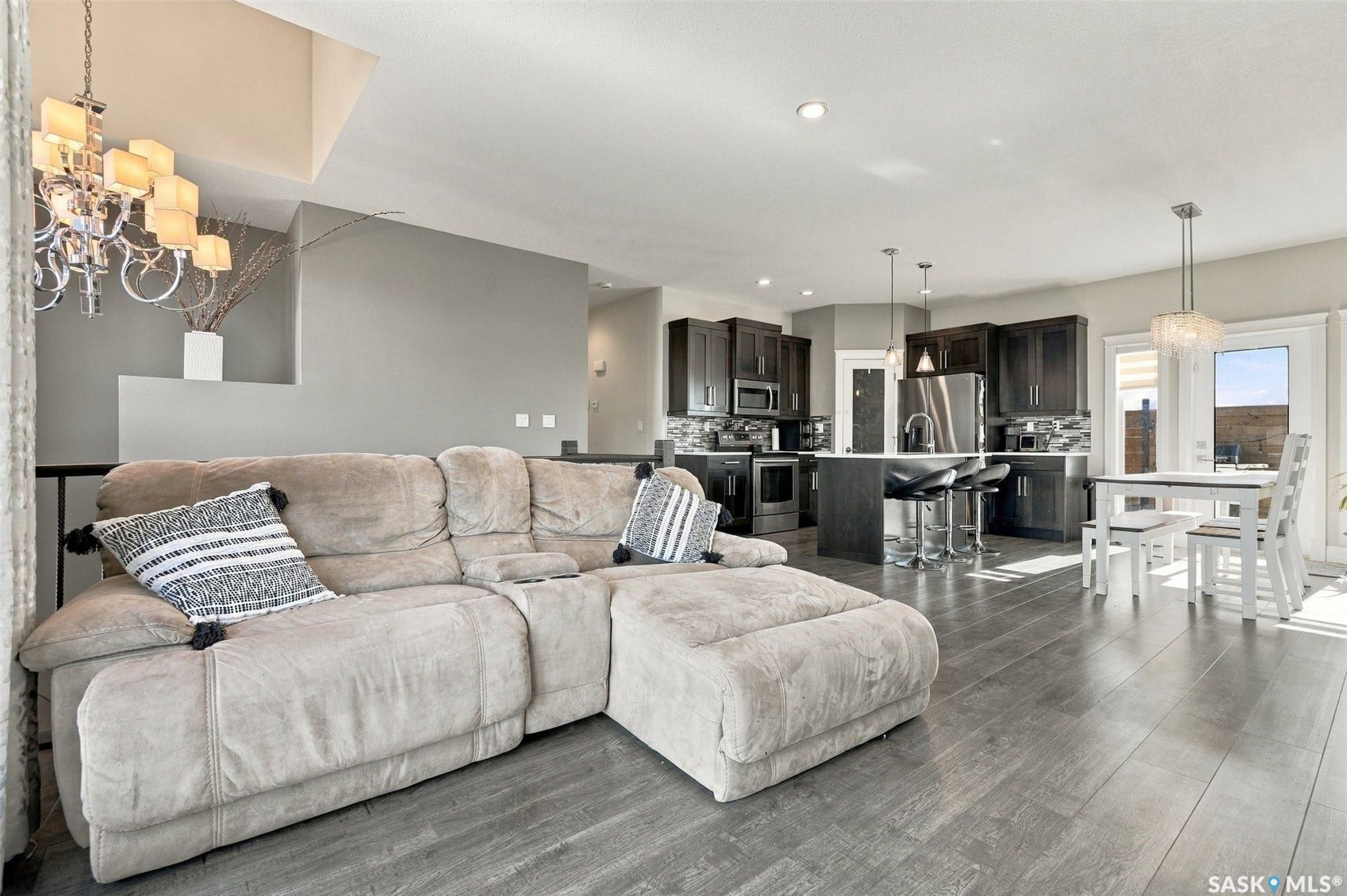 Wood-finish flooring throughout, with a contemporary kitchen featuring dark cabinetry and stainless steel appliances