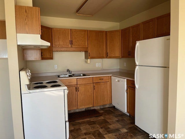 Kitchen featuring wood-finish cabinetry, solid surface countertops, a white electric range, a white dishwasher, and a white refrigerator