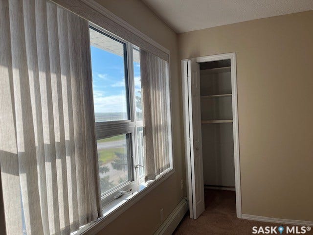 Picture window with vertical blinds, built-in closet with bi-fold doors, and neutral wall tones