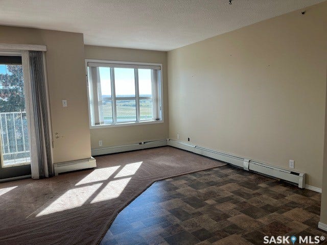Large windows, sliding glass door, patterned floor tiles, neutral wall paint, radiator heating
