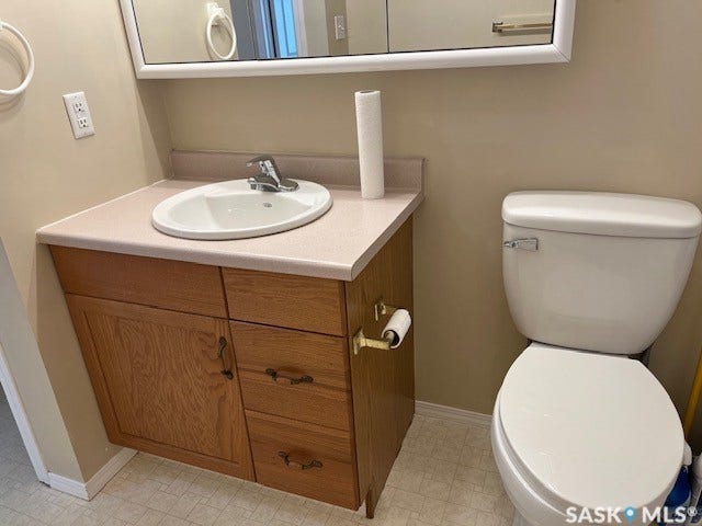 Vanity with wood-finish cabinetry, a single basin sink, and a laminate countertop