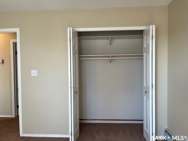Double bi-fold closet doors with interior hanging rods, light-toned wall paint, and brown carpet flooring