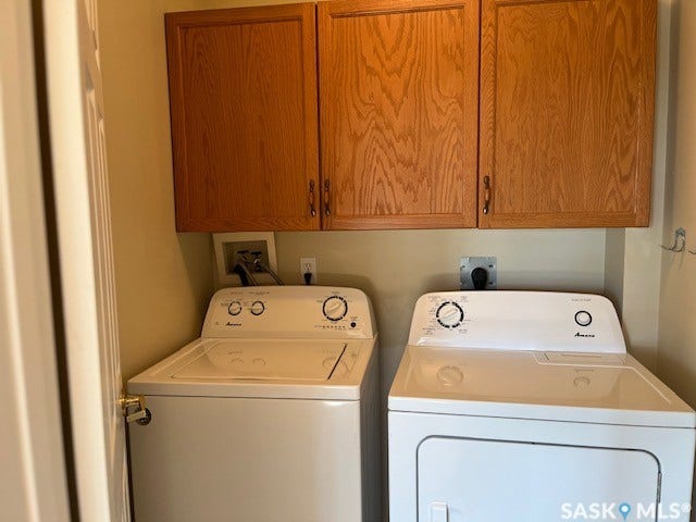 Dedicated laundry area with upper wood-finish cabinetry