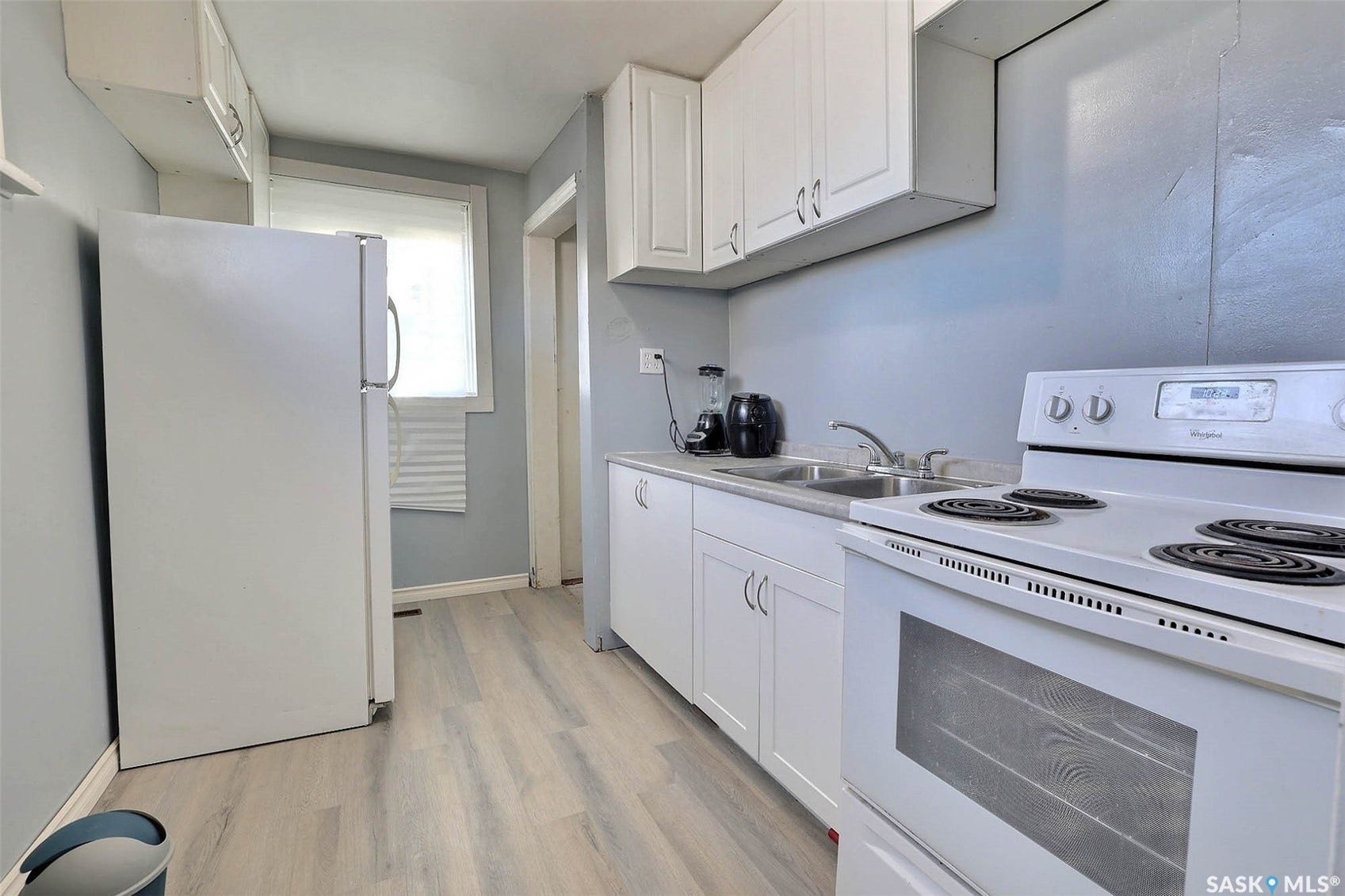 Kitchen featuring wood-finish flooring, white cabinetry, a double basin stainless steel sink, and a white electric range