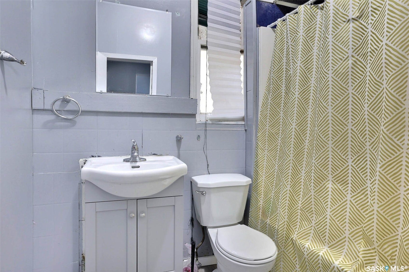 Ceramic tile walls featuring a mounted vanity with a basin sink, and a toilet