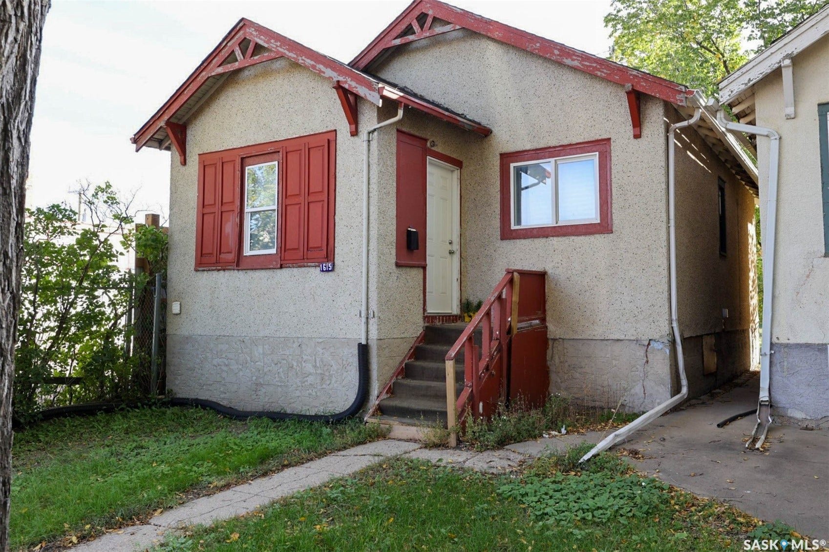 Stucco exterior with red trim accents, front steps with railing, and a concrete pathway