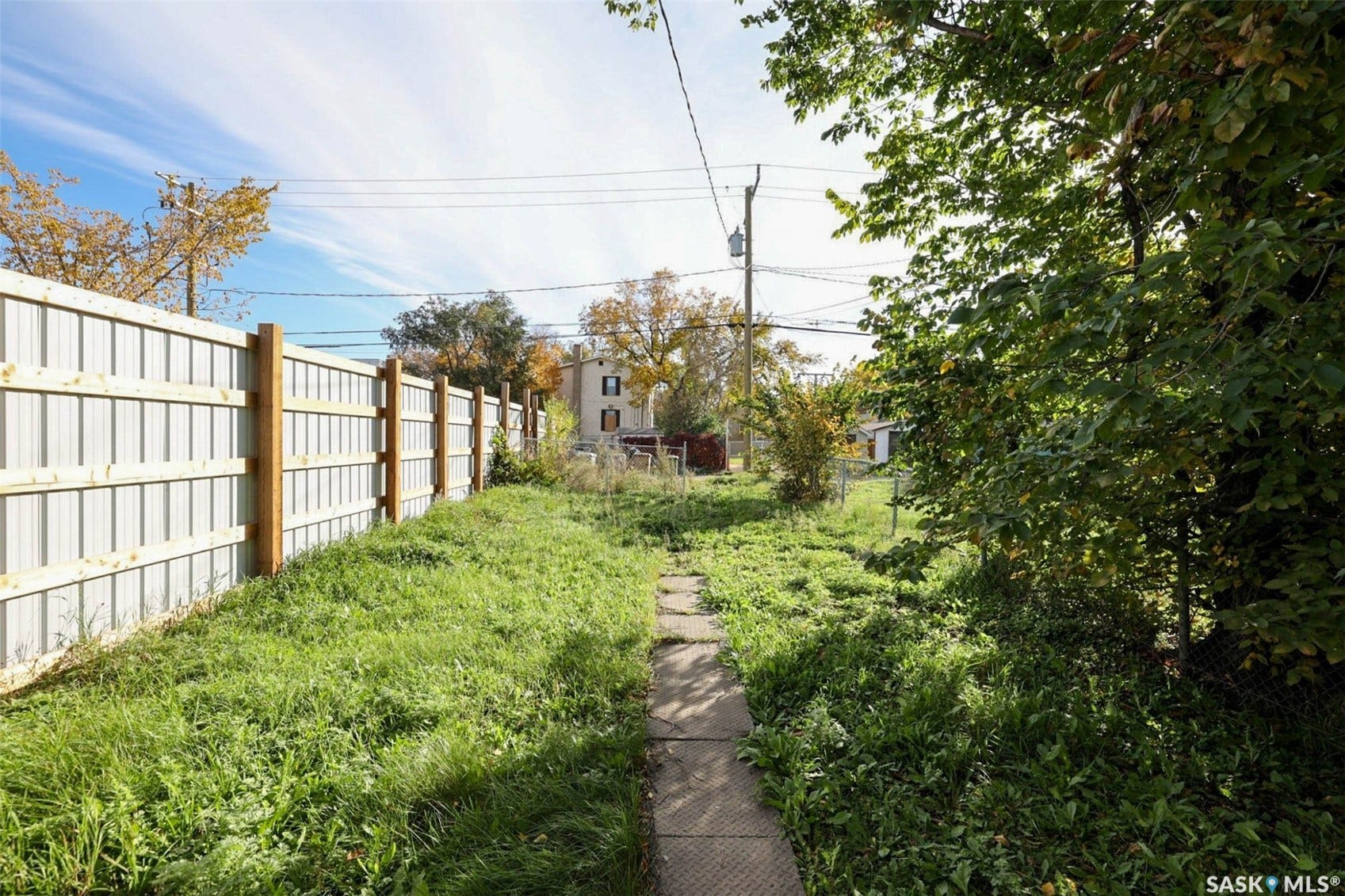 Expansive property featuring a path, a newly installed privacy fence, and mature trees