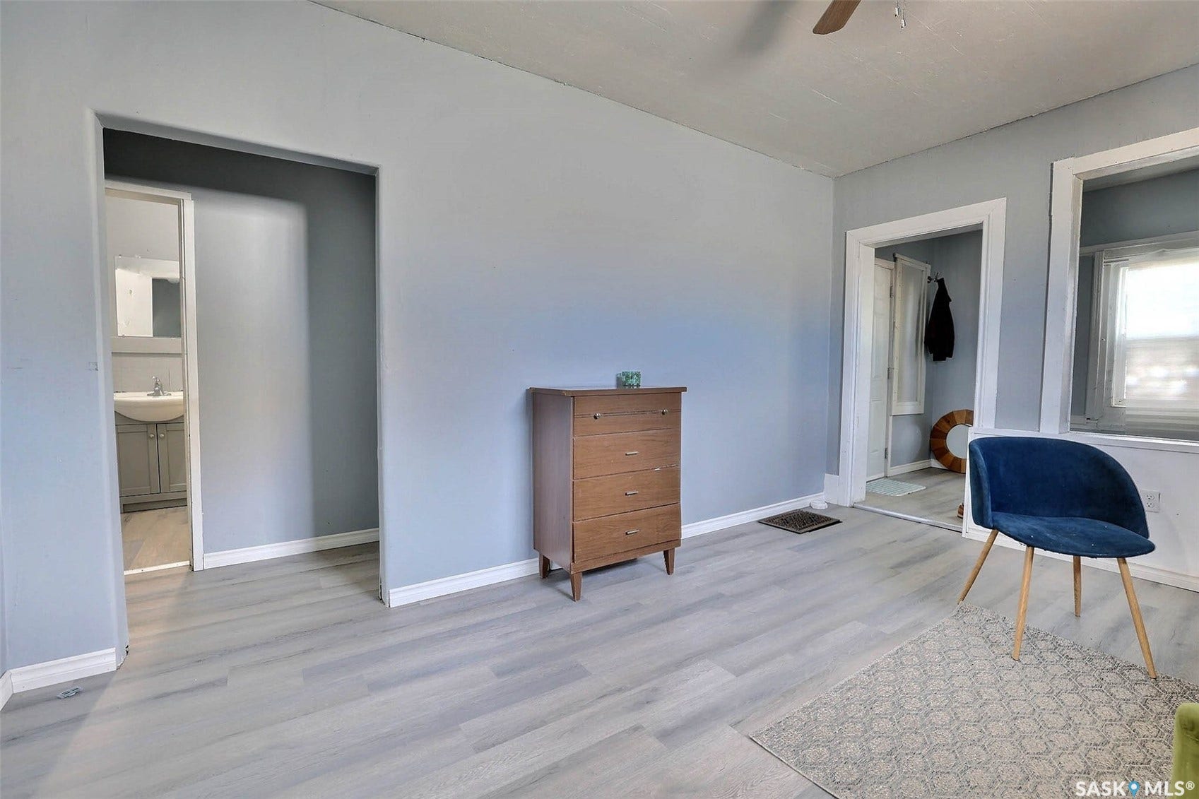 Light-toned wood-finish flooring, light blue wall paint, and white trim throughout