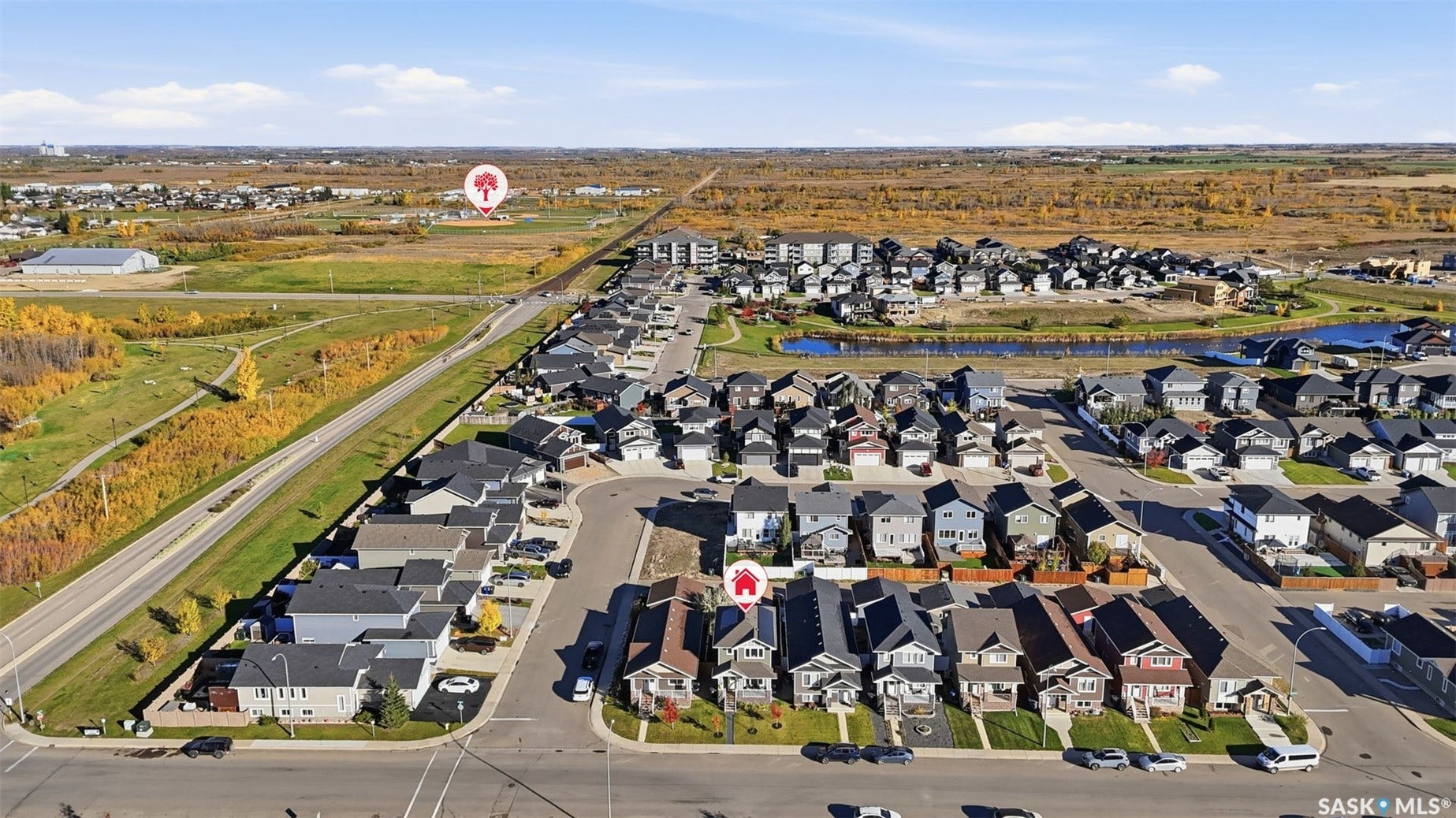 Aerial perspective of a developed residential area with multiple detached properties, paved roads, and natural green spaces