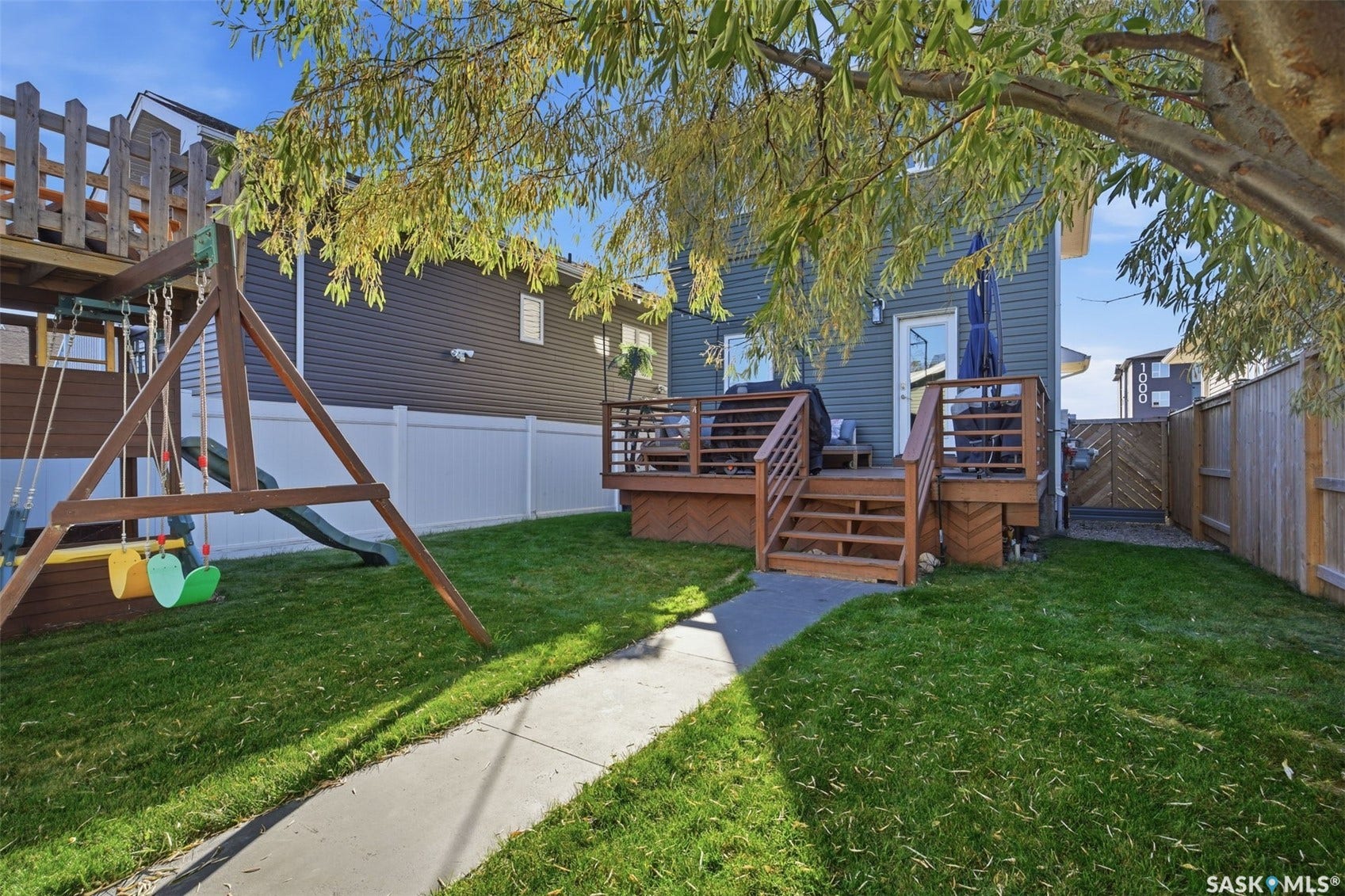 Expansive backyard featuring a manicured lawn, a multi-level wooden deck, and a privacy fence