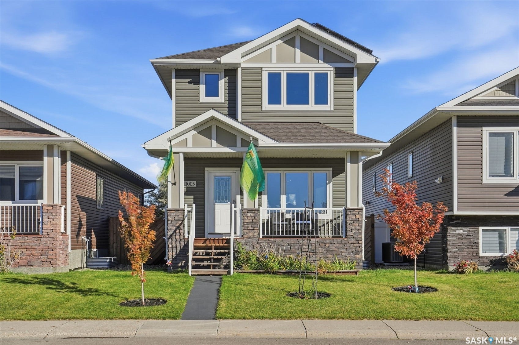 Two-story residence featuring a covered front porch with white railings, stone and siding exterior, multiple windows, and a paved walkway