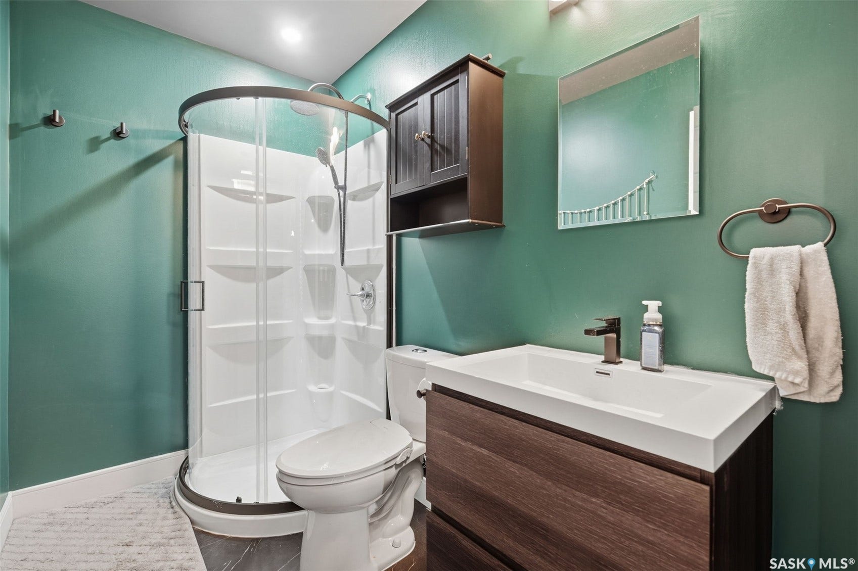 Corner shower enclosure, floating vanity with integrated sink, dark wood-finish cabinetry, and wall-mounted mirror