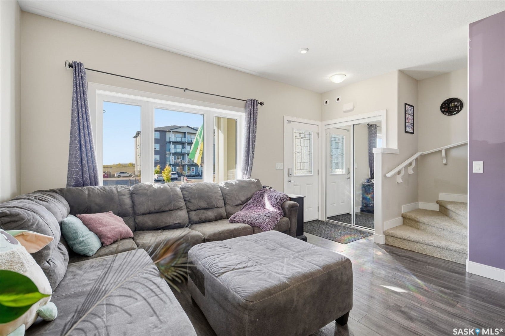 Wood-finish flooring, large multi-pane window, double entry doors with decorative glass inserts, mirrored closet doors, and carpeted staircase with white handrail