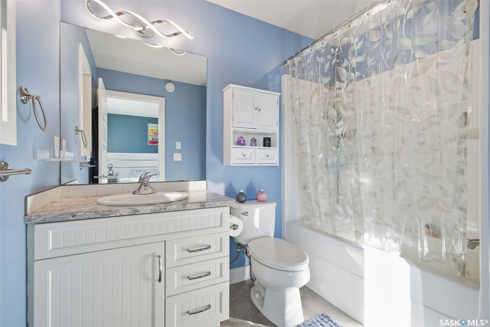White vanity with beadboard paneling, integrated sink, and chrome fixtures