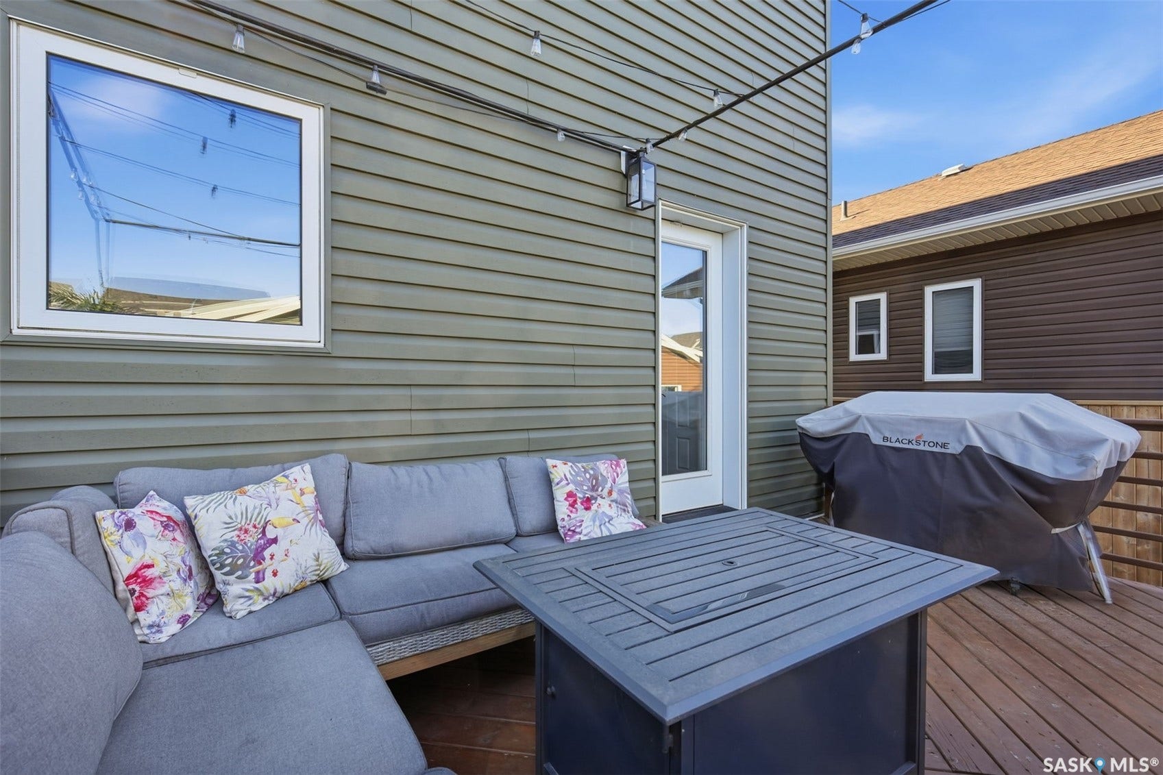 Private deck with wood-finish flooring, featuring a solid exterior door and horizontal siding