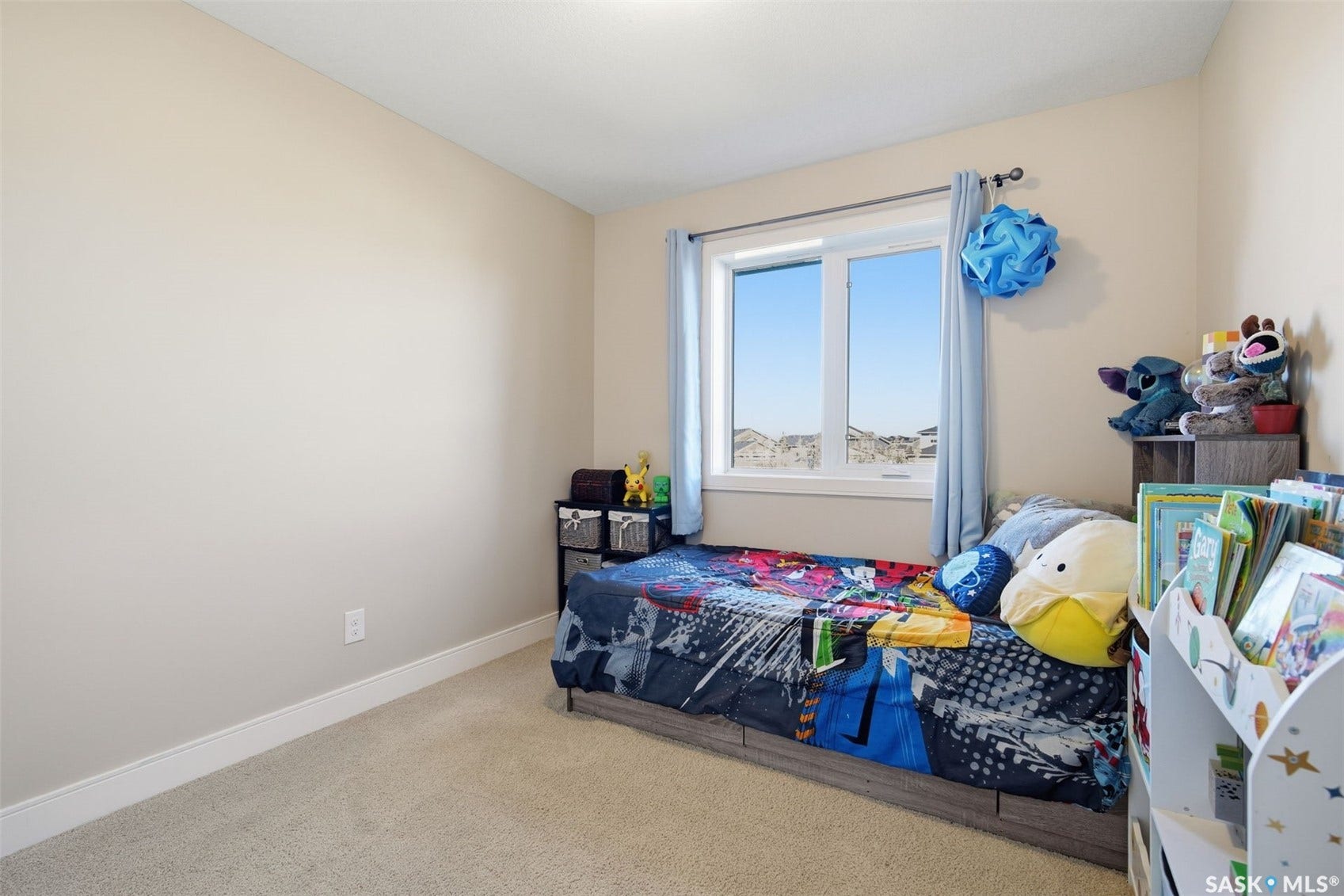 Carpeted flooring with light-colored walls, featuring a window with a white frame and light blue drapes