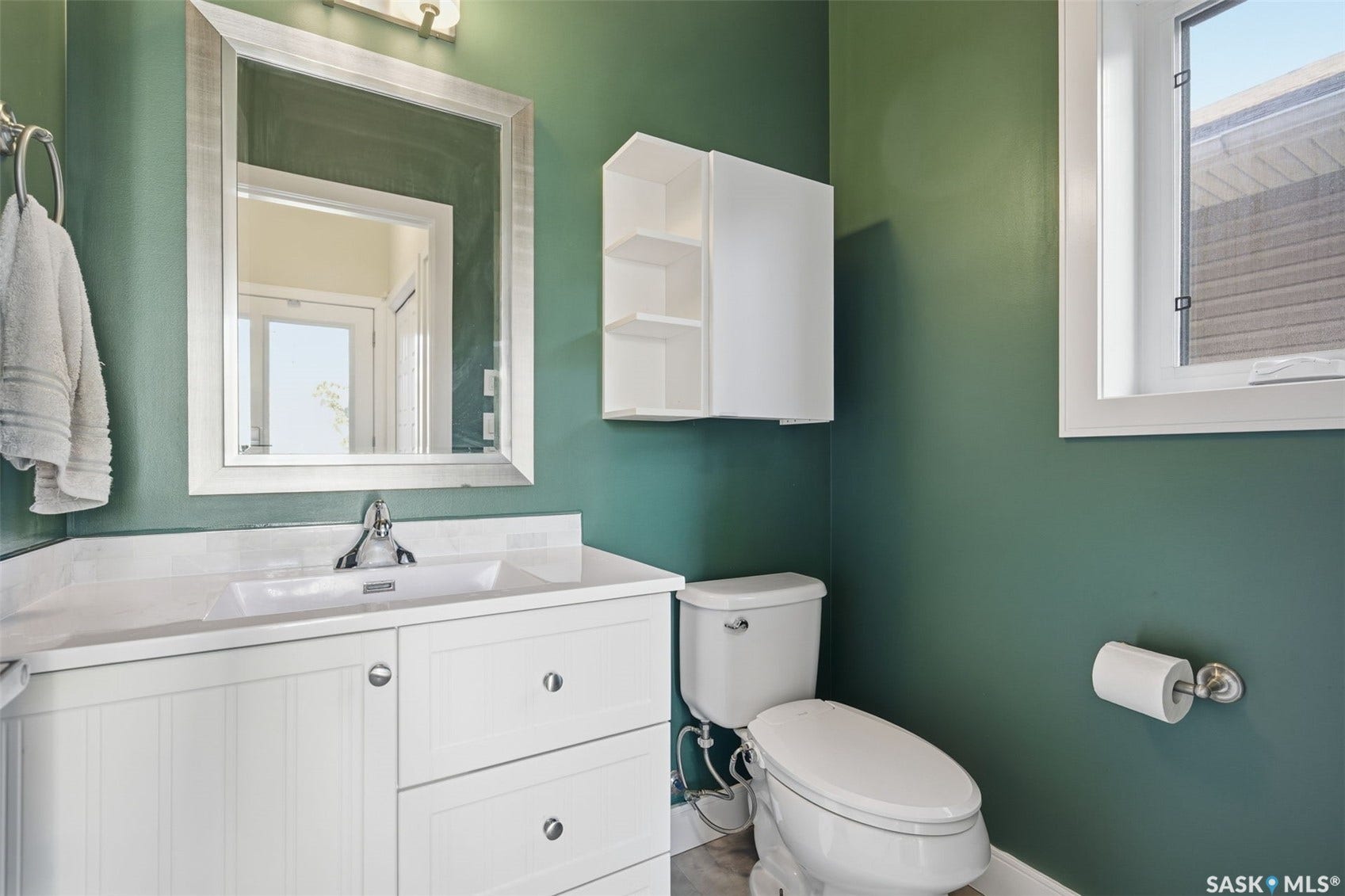 White vanity with a single basin sink, chrome faucet, and bright overhead lighting