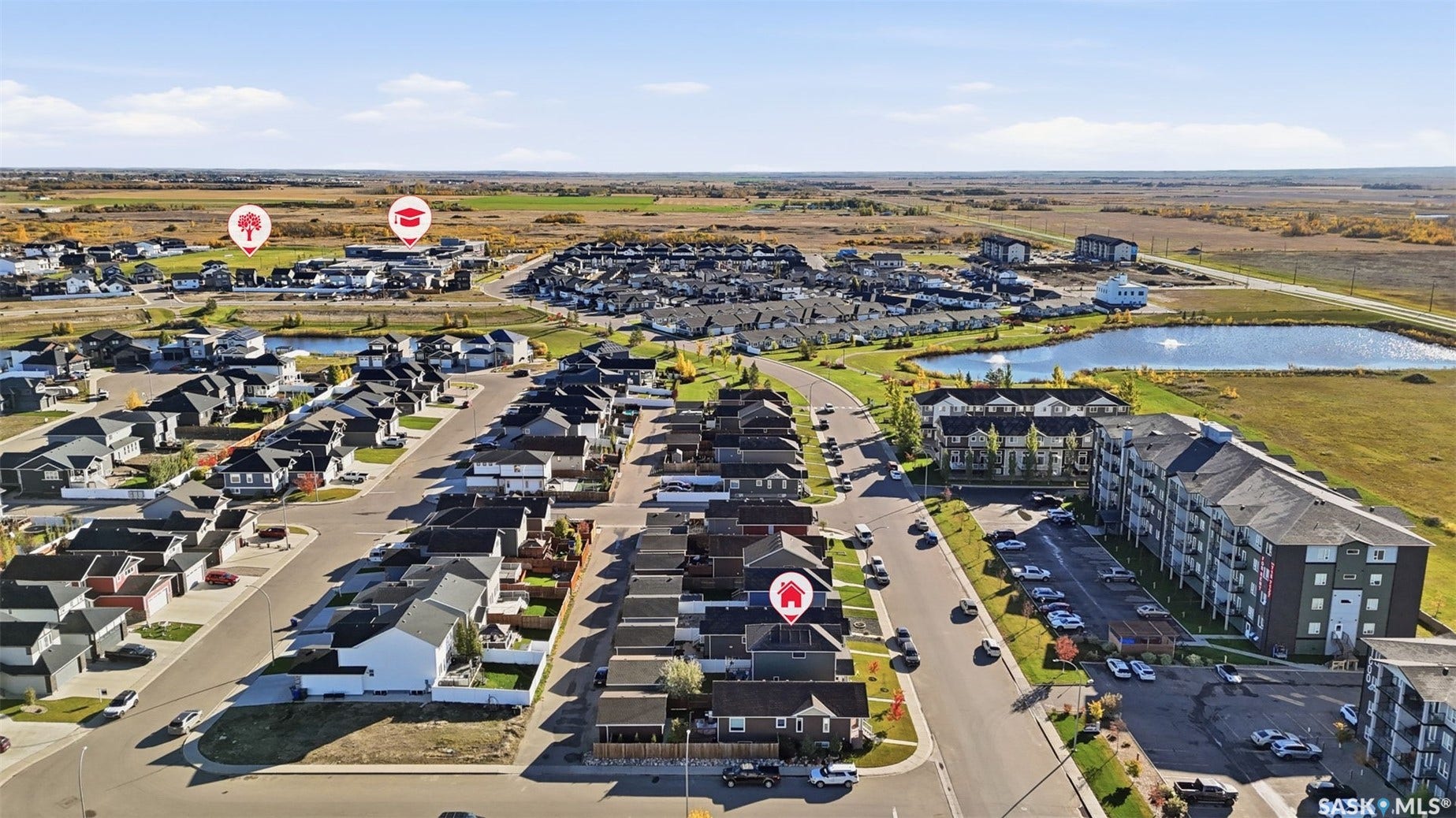 Residential community with modern single-family homes, multi-story residential buildings, and a visible pond feature
