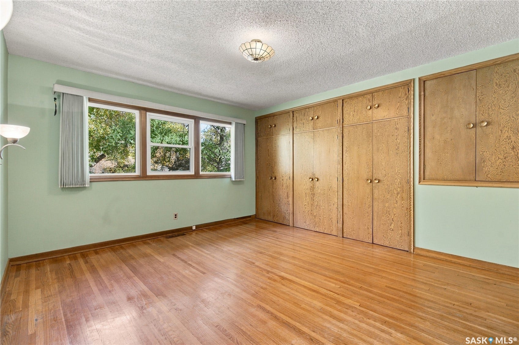 2727 Assiniboine Avenue, Regina SK S4S 1C7 Wood-finish flooring, built-in wooden cabinetry, multiple windows, and a ceiling-mounted light fixture